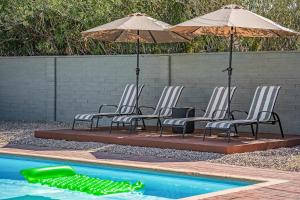 a group of chairs and umbrellas next to a swimming pool at Tucson Oasis by Rather Be Properties in Tucson