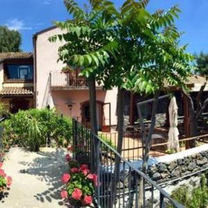 a house with a fence and a tree and flowers at Agriturismo Il Sole e Il sale in Acireale