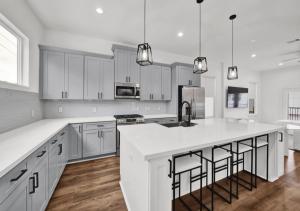 a kitchen with white cabinets and a kitchen island with bar stools at Modern Home Suite, 2BR, Office, Near Galleria in Houston