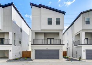 a large white apartment building with a garage at Modern Home Suite, 2BR, Office, Near Galleria in Houston