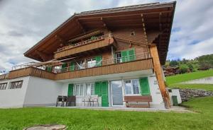 a house with a balcony with green and white at Lakeview Lodge Ferienwohnung Aeschlen ob Gunten am Thunersee in Aeschlen ob Gunten