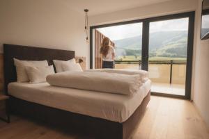 a woman standing in a bedroom with a large bed at Sottla - your mountain home in Valdaora