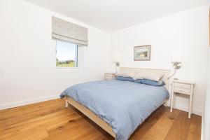 a white bedroom with a bed and a window at Golden Strand View in Doogort