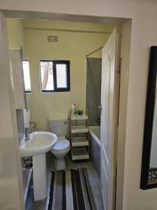 a bathroom with a sink and a toilet and a tub at Ahava Home in Lusaka
