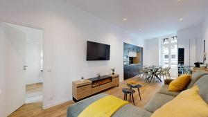 a living room with a couch and a tv on a wall at expat renting - La Rotonde - Prestige - Netflix in Toulouse