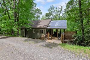 a green cabin in the woods with a porch at By The New River - Hot Tub - Fireplace - Covered Porch in Glendale Springs