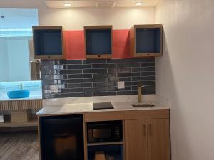 a kitchen with a sink and two monitors on the wall at Rodeway Inn Encinitas North in Encinitas +72 photos