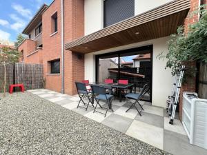 un patio con tavolo e sedie all'esterno di un edificio di Maison à Toulouse - Cottage - COTKAFTLS00 MAE-7531 a Tolosa