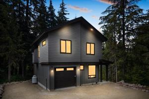 ein schwarzes Haus mit einer Garage im Wald in der Unterkunft 3 Br Sleep 8 Hot Tub Fire Pit Stunning Views in Government Camp