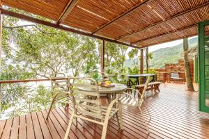 a patio with a table and chairs on a deck at Refúgio pé na areia na Caieira - Espaço completo in Florianópolis