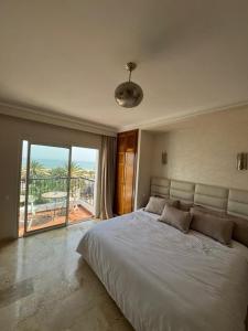 a bedroom with a large white bed and a balcony at marina1 in Agadir