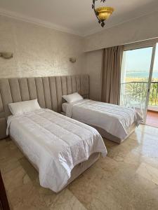 two beds in a hotel room with a balcony at marina1 in Agadir