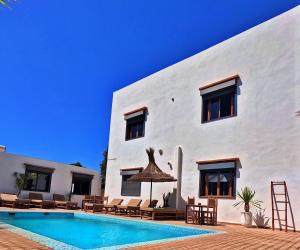 a villa with a swimming pool in front of a building at Dar Iziki in Sidi Kaouki