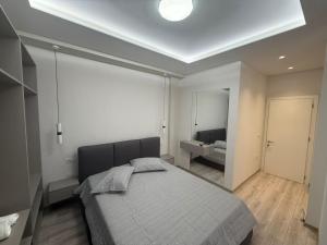 a bedroom with a bed and a bathroom with a sink at Amaji Apartament Korcë in Korçë