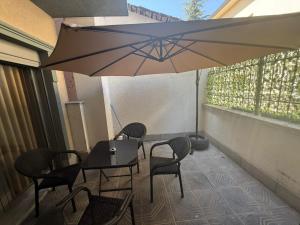 a patio with a table and chairs and an umbrella at Amaji Apartament Korcë in Korçë