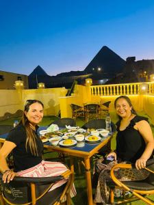 two women sitting at a table with plates of food at Sidi Hamad Pyramids View in Cairo