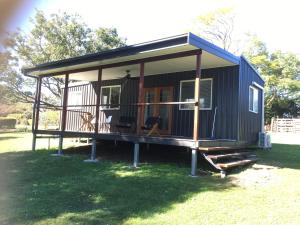 a blue tiny house with a porch on the grass at Golf Links Sunset Cabin 