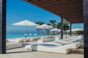 a row of white lounge chairs and umbrellas at a resort at Nuevo Vallarta Beachfront Studio - Aria Ocean in Nuevo Vallarta 