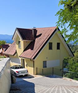 a yellow house with a car parked in a driveway at Hillhouse Novo mesto in Novo Mesto