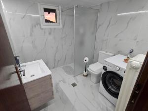 a white bathroom with a washing machine in it at Chrysalis Apartment in Nea Potidaea
