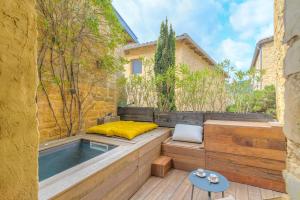 a patio with a bed and a hot tub at L'Arche Dorée in Pouilly-le-Monial