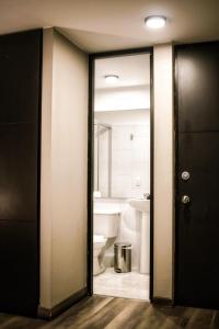 a bathroom with a toilet and a sink and a mirror at Hemma Bogotá Chapinero Premium Suites Hotel in Bogotá