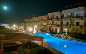 a swimming pool in front of a building at night at TAVIRA Rass Suder"For Family" in Ras Matarma