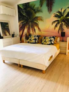 una camera da letto con un grande letto con palme sul muro di Joli oasis au centre de l'île a Baie-Mahault Altre 47 foto