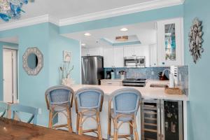 a kitchen with blue walls and a counter with four chairs at Updated direct oceanfront corner with a wrap-around balcony, heated pool and beach access in Bottle Island