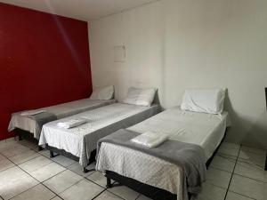 a room with three beds and a red wall at Hotel Paradão Linhares in Linhares