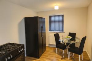 a kitchen with a black refrigerator and a table with chairs at Cosy 3 Bed House, Decked Garden, Free Parking in Central Station +5 photos