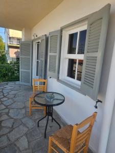 a patio with a table and chairs and windows at Chrysalis Apartment in Nea Potidaea
