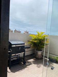 a patio with a grill and a plant on a balcony at Apartamento Amplo in Natal