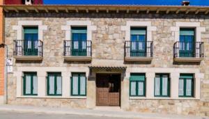 a stone building with windows and balconies on it at Tio Claudio in El Barraco
