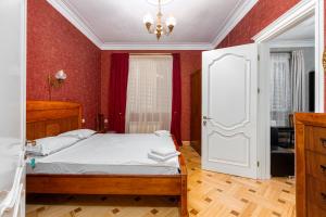 a bedroom with a bed with red walls and a chandelier at Charming Private House Pekini av in Tbilisi City