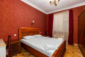 a bedroom with a large bed with red walls at Charming Private House Pekini av in Tbilisi City