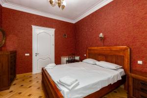 a bedroom with a large bed with red walls at Charming Private House Pekini av in Tbilisi City
