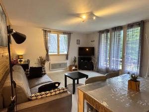 una sala de estar con un sofá y una mesa en T2 ensoleillé. Terrasse, jardin commun, vue, parking., en Cauterets