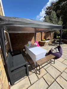a white table and chairs under a black canopy at Willow Tree Retreat Airport Friendly 3BR House, with Garden & Office in Northolt