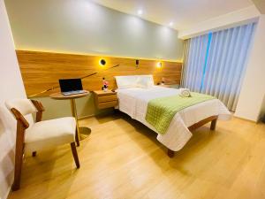 a bedroom with a bed and a desk with a laptop at HOTEL ALTIVA - Arequipa in Cayma