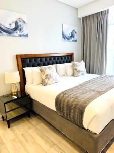 a bedroom with a large bed with a black headboard at Menlyn Maine Residences in Pretoria