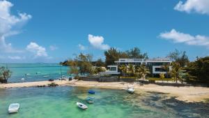 una casa en una playa con barcos en el agua en Pointe d'Azur Beachfront Homes - Pereybere, en Grand Baie