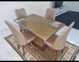 比绍Guest house的地毯上摆着一张玻璃桌和四把椅子