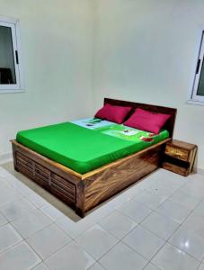 a bed with a green mattress and pink pillows on it at Guest house in Bissau