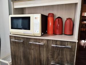 a microwave and red vases sitting on a shelf at Chácara com piscina área de lazer completa estilo rústico em Socorro in Socorro