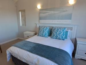 una camera da letto con un letto grande con cuscini blu di Romansbaai Beach House a Gansbaai