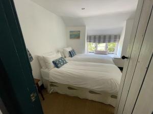 a small bedroom with a bed with a window at Buckley Cottage, Batson Salcombe in Salcombe