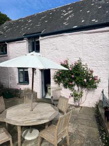 a wooden table with an umbrella in front of a house at Buckley Cottage, Batson Salcombe in Salcombe