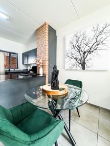 a living room with a glass table and green chairs at Executive Apartment at Waterfall Ridge in Midrand