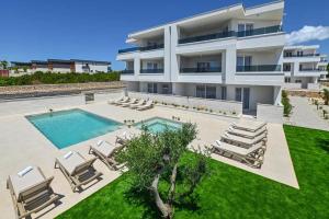 ein großes weißes Gebäude mit einem Swimmingpool und Liegestühlen in der Unterkunft Villa Gaj 2 in Novalja
